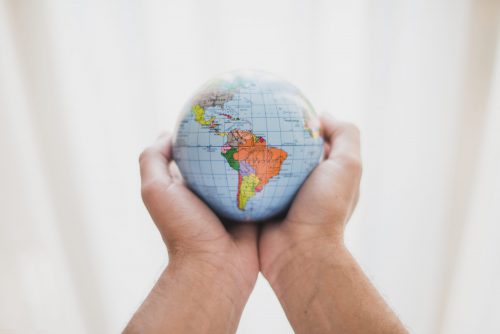 person-s-hand-holding-small-globe